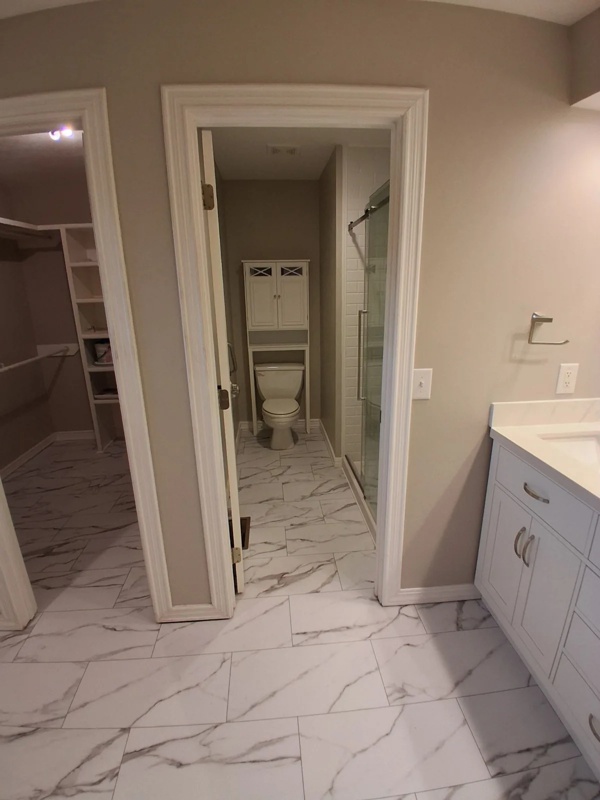 Vanity at the entrance to a tiled bathroom and adjoining closet