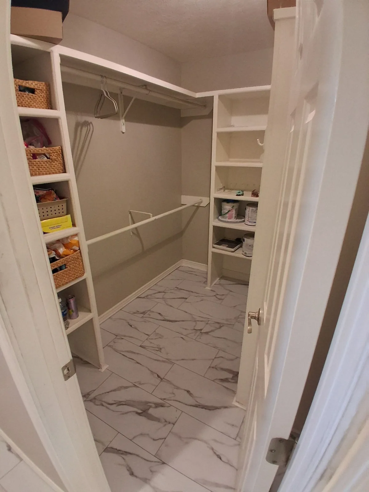 Finished closet shelving and hanging rods above marble-look floor tile