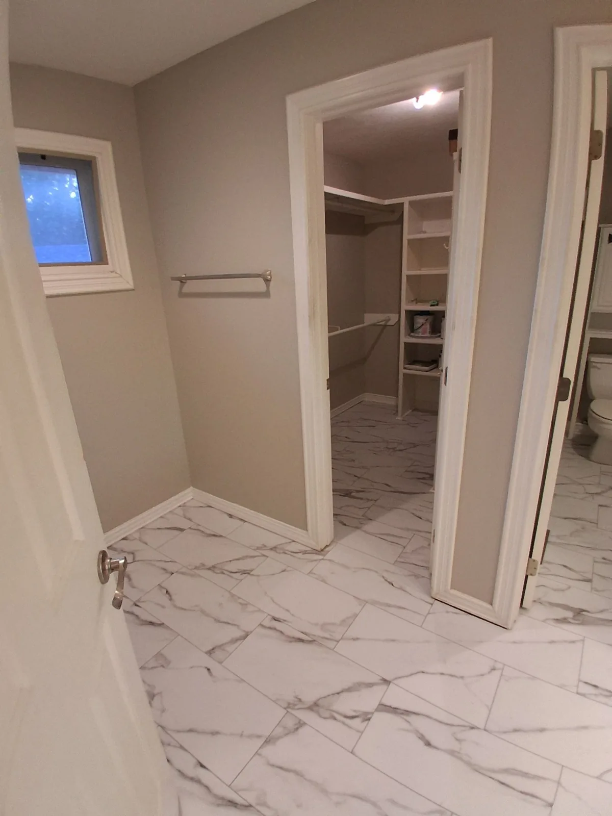 Marble-look floor tile connecting the bathroom and open closet doorway